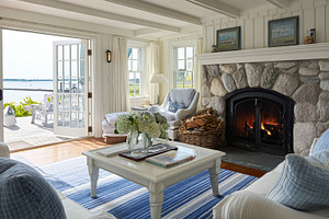 Cozy coastal living room featuring stone fireplace and ocean vie, a Photo by Studio ANNA