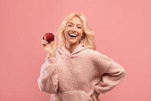 Detox concept. Portrait of excited woman holding ripe apple and smiling at came, a Photo by Prostock-Studio