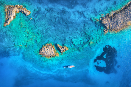 Aerial view of beautiful yacht on the sea and rocks at sunset, a Nature Photo by den-belitsky