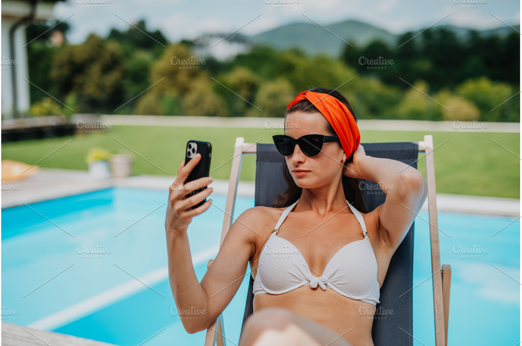 Young woman sitting by swimming pool, a Person Photo by HalfPoint