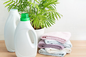 Laundry cleaning products with folded towels and plant, an Industrial Photo by Olena Rudo