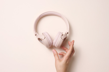 female hand hold pink wireless headphones on a beige background,, a Technology Photo by ndanko