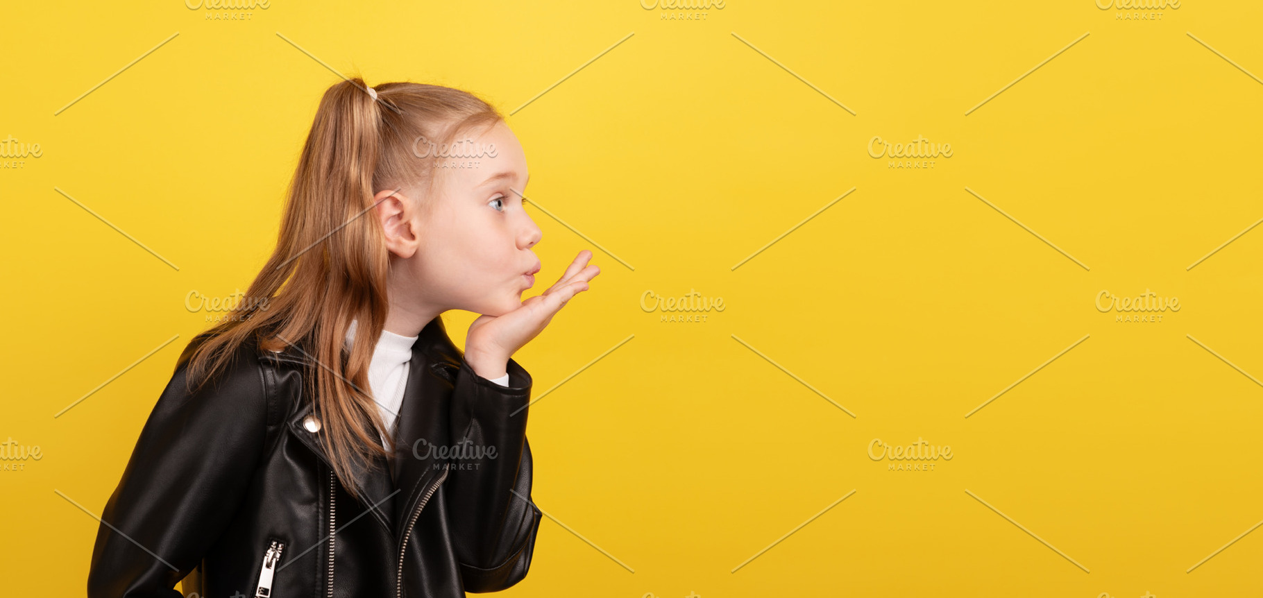 Side view of a young girl in a black leather jacket blowing a ki, a Person Photo by Ales Munt