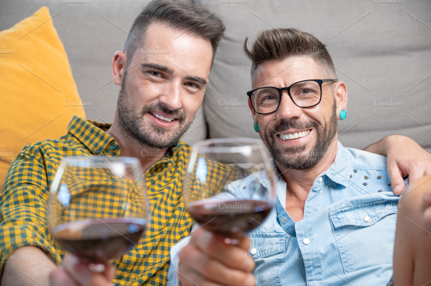 Gay couple in love sitting at home on the floor and toasting with red wine., a Person Photo by david.herraez.calzad