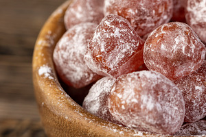 sweet dehydrated candied fruits of kumquat in white powdered, close up in a bow, a Photo by rsoollAI
