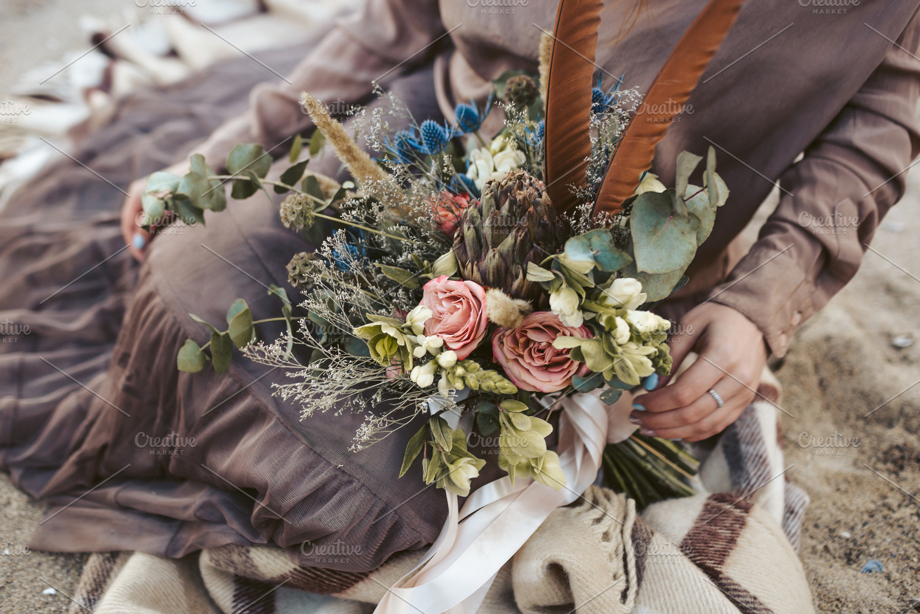 Bride in brown clothes with a rustic bouquet sit on the sand artwork country, a Person Photo by Stahov