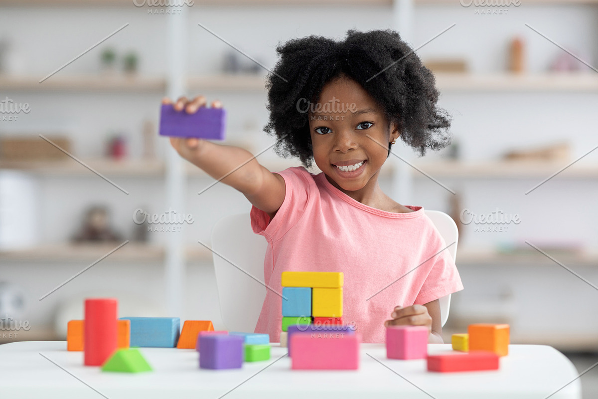 Cute little black girl showing purple wooden block, a Photo by Prostock-Studio (Photo 2 of 2)