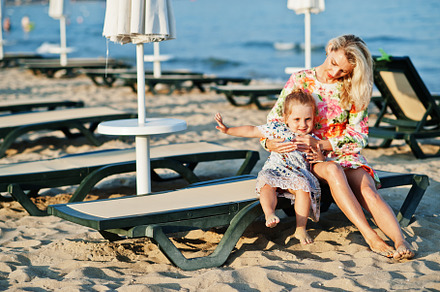 Mother and beautiful daughter having fun on the beach, sitting o, a Person Photo by AS photostudio