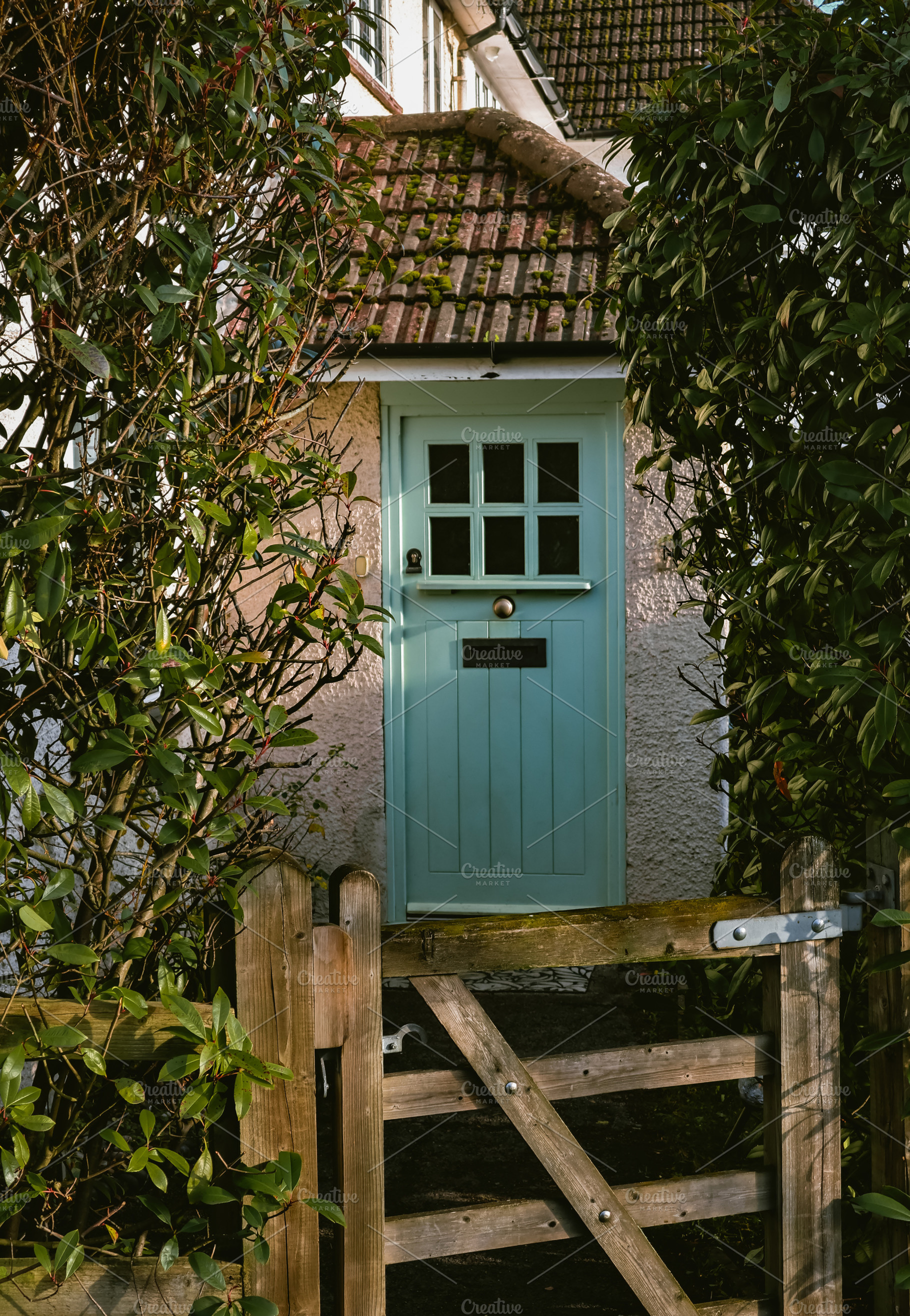 Green cottage door with roof and wooden gate, providing privacy, a Photo by Studio ANNA