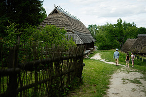 Kids strolling through a rustic village garden with traditional wooden cottages, a Person Photo by AS photostudio