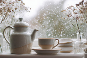 Teapot, cup, and dried flowers on a white windowsill, creating a, a Photo by Studio ANNA