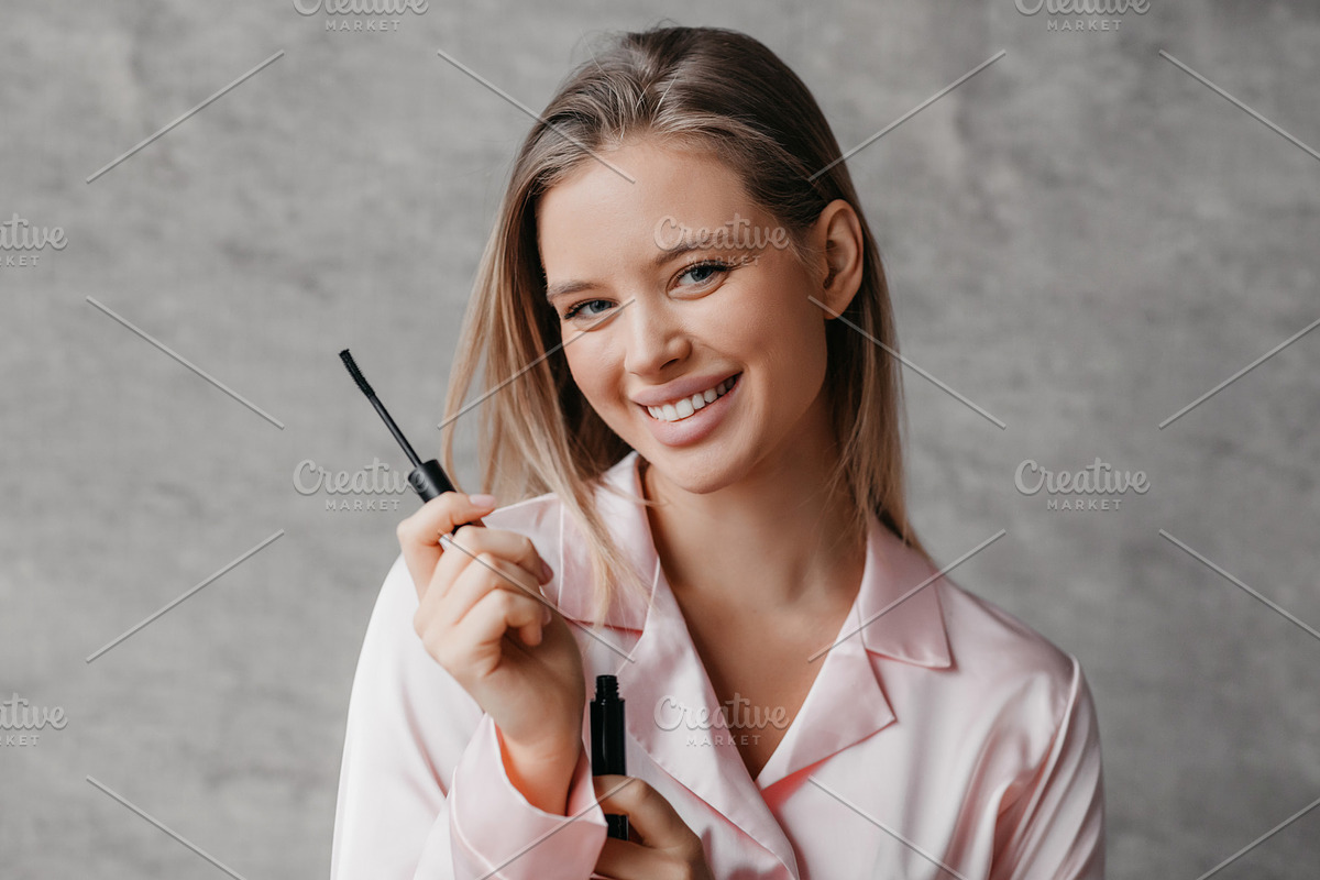 Lovely young lady holding mascara and smiling at camera, applying makeup after, a Photo by Prostock-Studio (Photo 2 of 4)