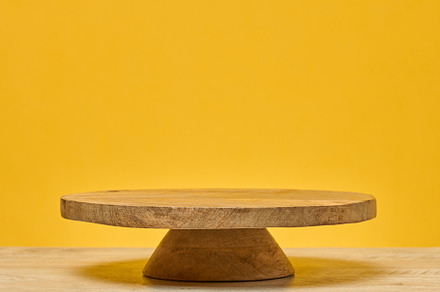 Wooden round podium on wooden table, on bright yellow background