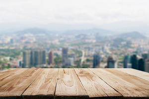 Wooden surface on blurred background of city, mountains, sky.
