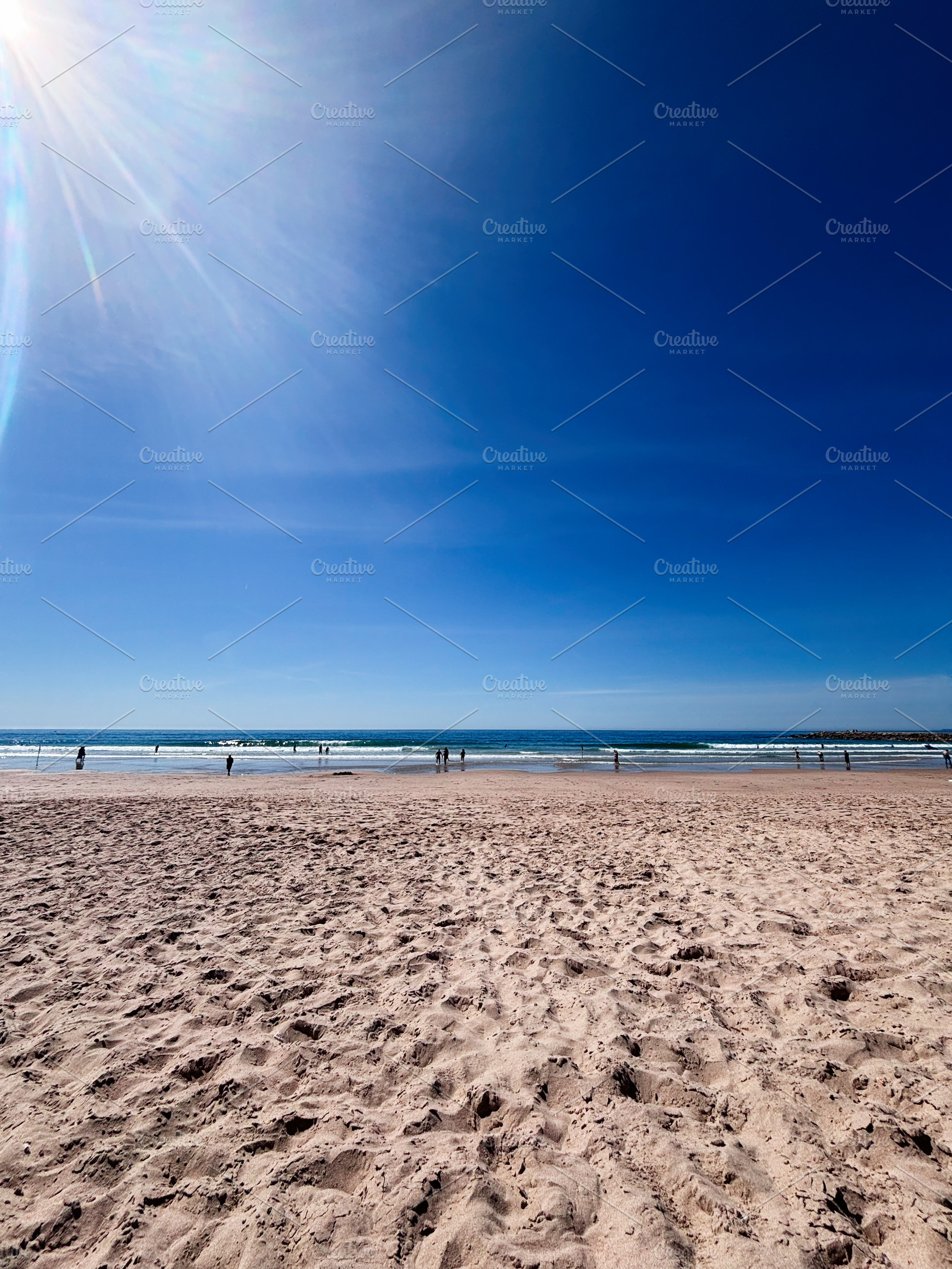 Sunny Lisbon Portugal beach scene with blue sky, sunlit shore, and people enjoy, a Photo by AS photostudio