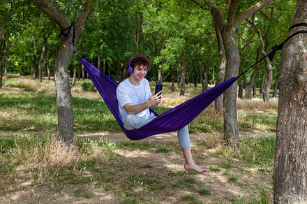 A young guy with curly hair is relaxing on a hammock on a hot summer day., a Person Photo by Photostock