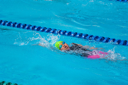 Swimmer child swims backstroke swimming style in a race swimming