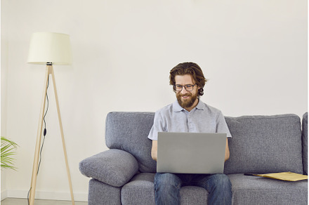 Smiling millennial man uses laptop, a Person Photo by StudioRomantic