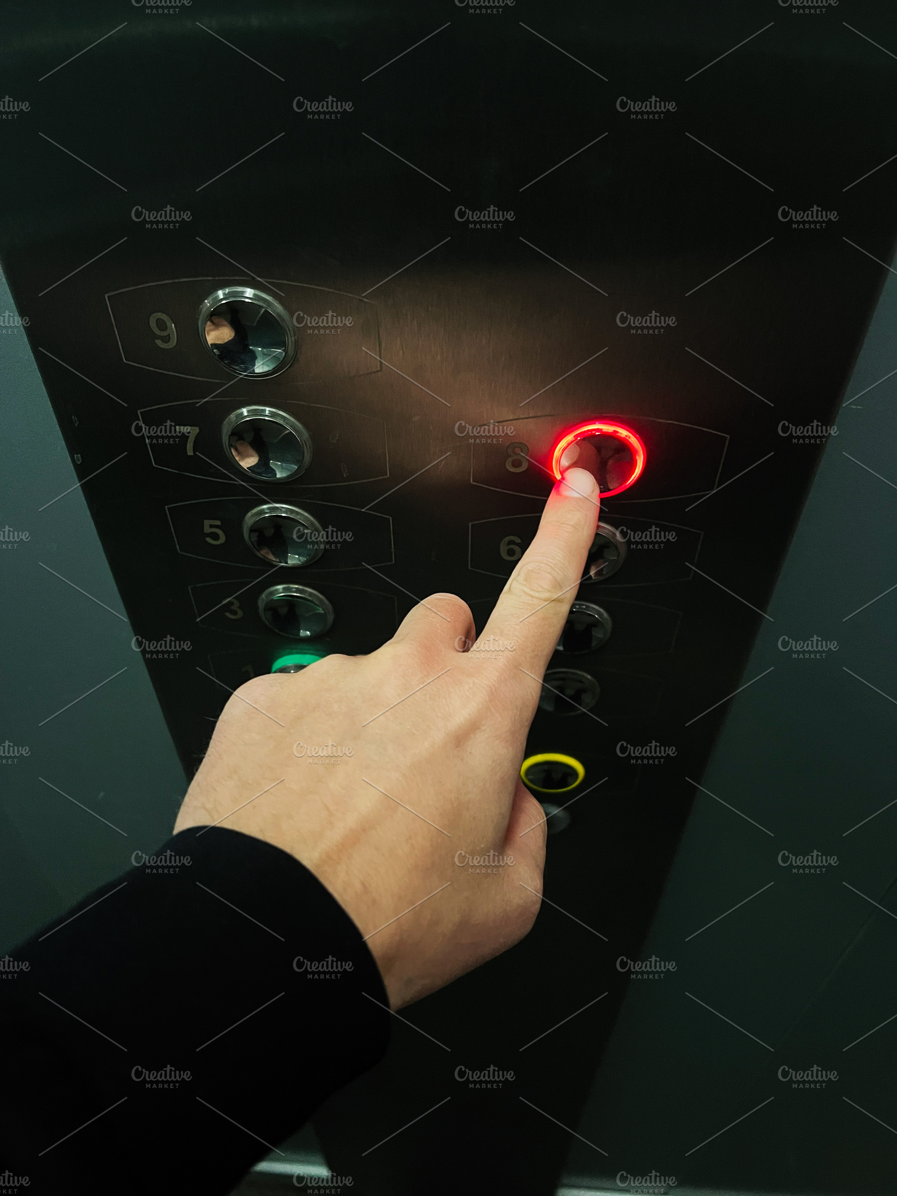 Person pressing elevator button illuminated with red light for eighth floor, a Photo by AS photostudio