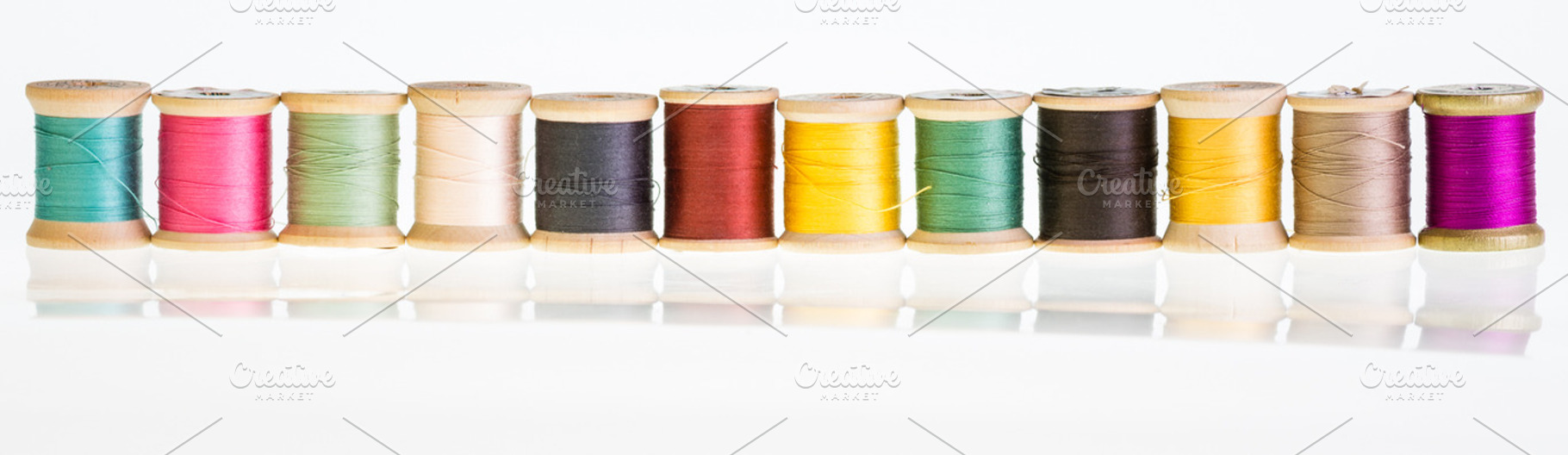 Row of thread spools with reflection
