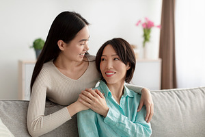 Portrait of lovely young Asian woman hugging her mature mother at home. Family, a Photo by Prostock-Studio