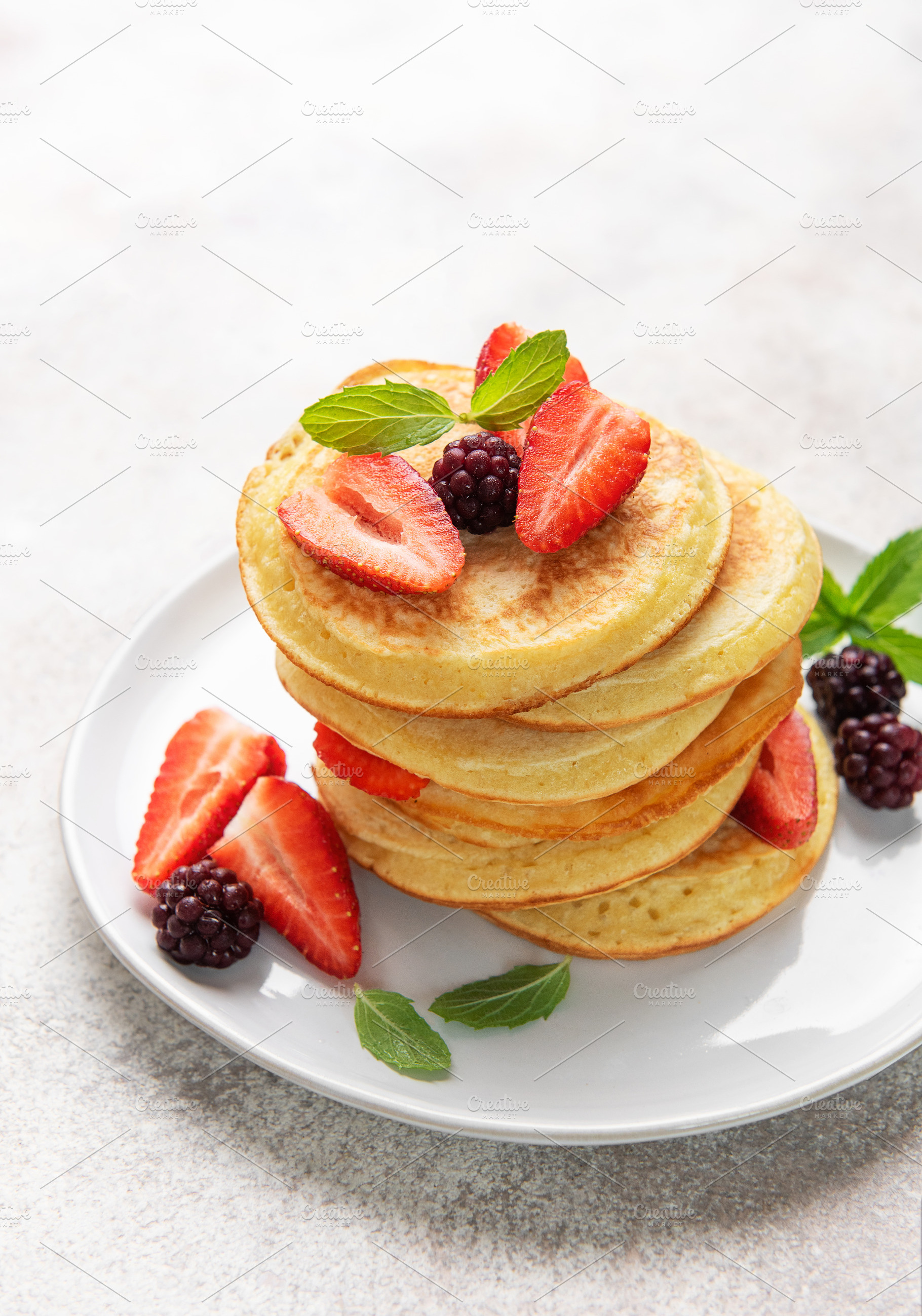 Stack of pancakes with fresh berries and mint, a Food & Drink Photo by Olena Rudo