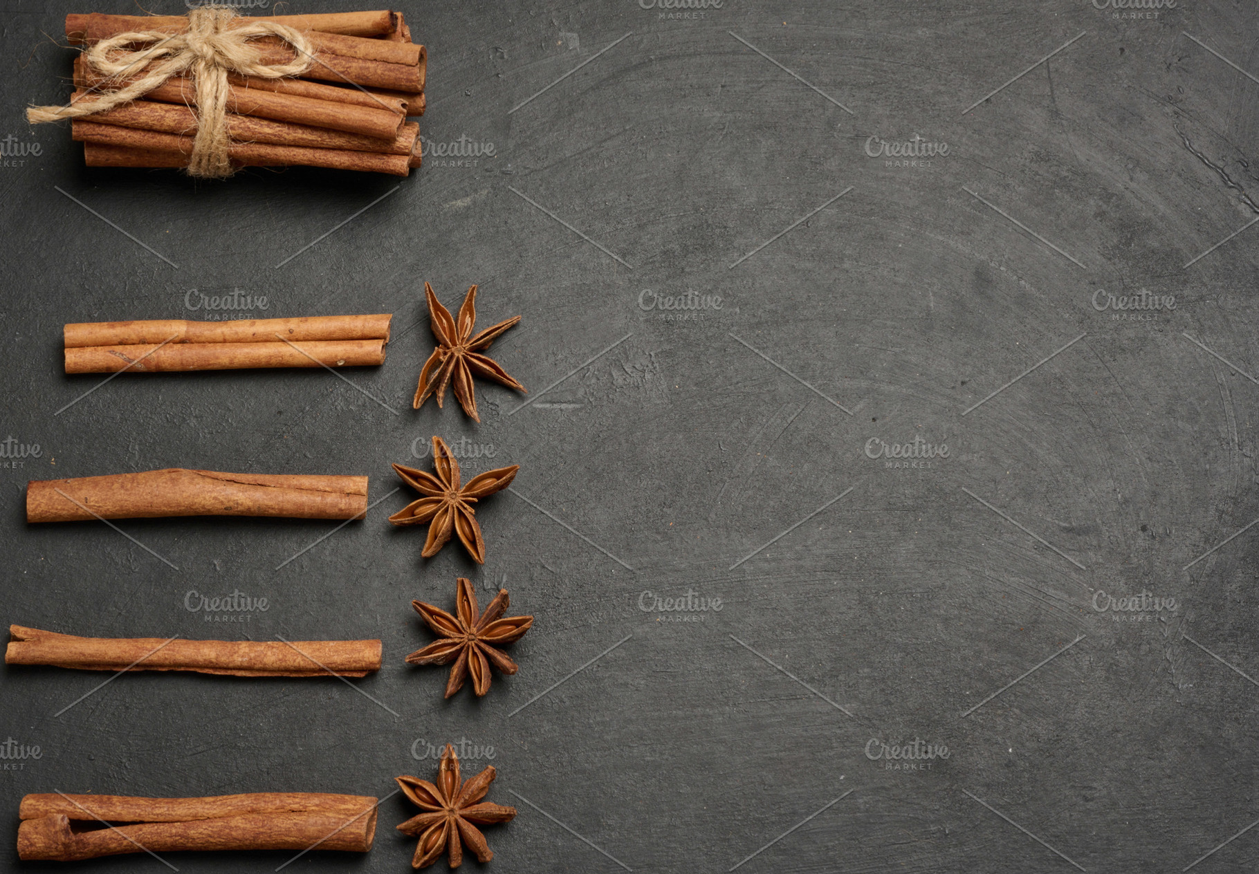 Cinnamon sticks and star anise are scattered on a dark, textured, a Food & Drink Photo by ndanko