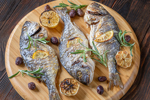 Three roasted sea bream with lemon rosemary olives and garlic on