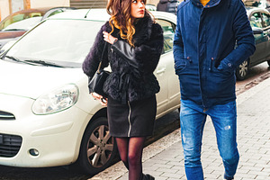 Young couple walking and talking on city sidewalk, a Person Photo by Antonio Gravante Market