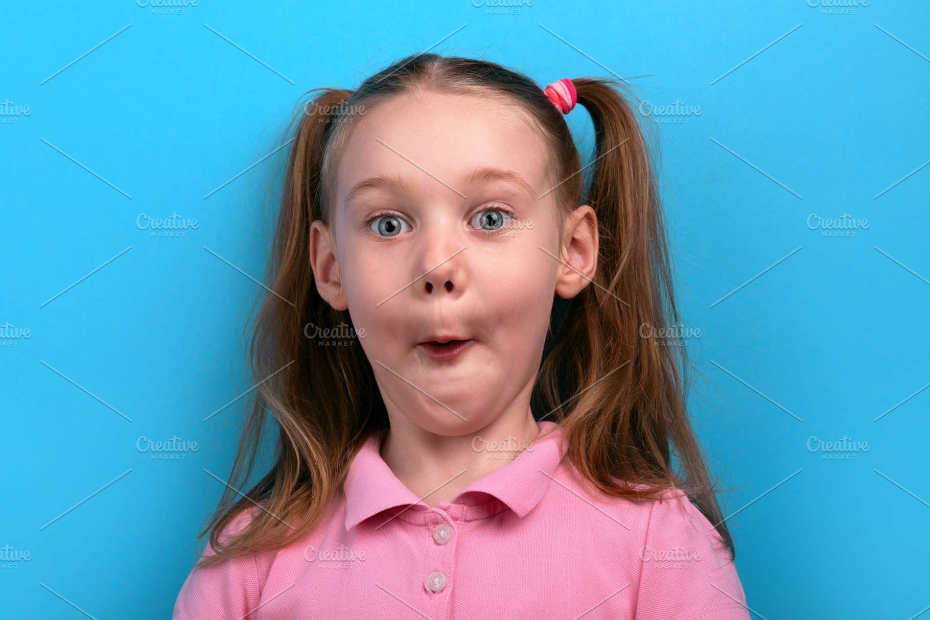 Funny close-up of a young girl in a pink shirt making a surprise, a Person Photo by Ales Munt