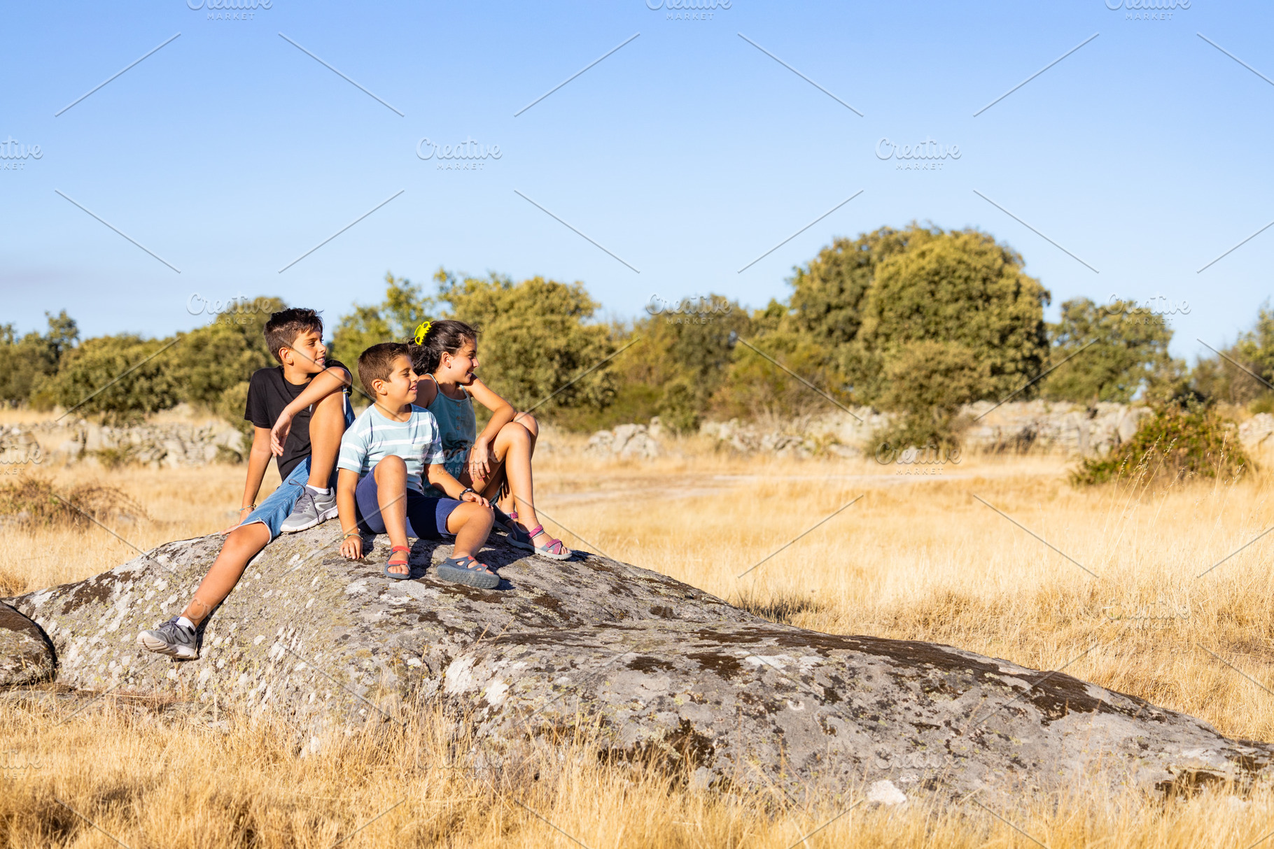 Three kids  with on a top of a rock on their summer vacation, a Person Photo by Cosca