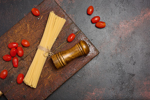 Uncooked spaghetti pasta tied with twine, cherry tomatoes, and a, a Food & Drink Photo by ndanko