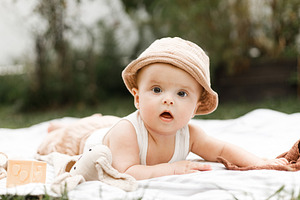 Beautiful happy baby in hat lying on blanket and playing with to, a Person Photo by Sonjachni
