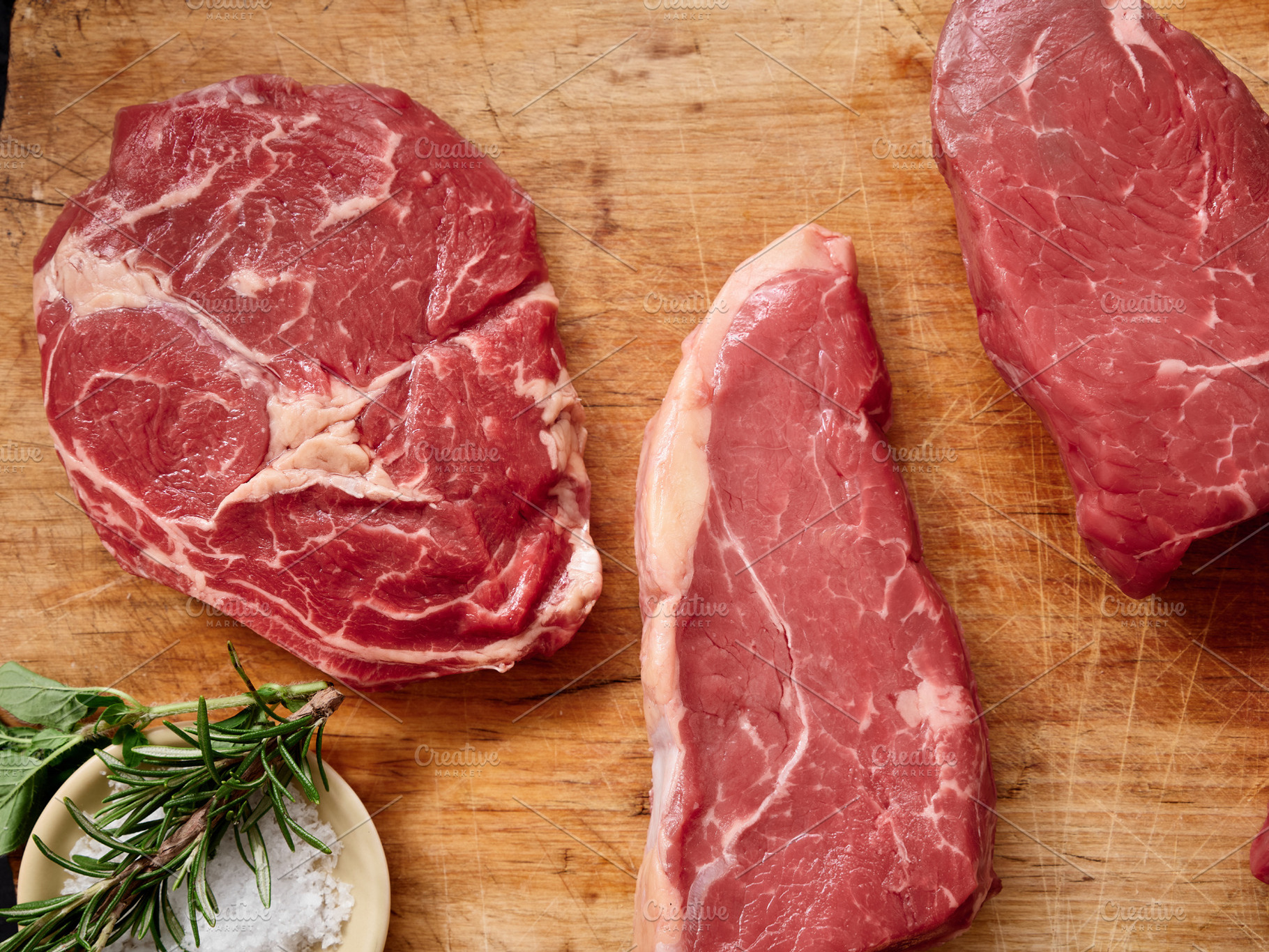 Raw rib-eye, roast beef, flank and rump steak on wooden cutting board in kitche, a Food & Drink Photo by Asya Nurullina