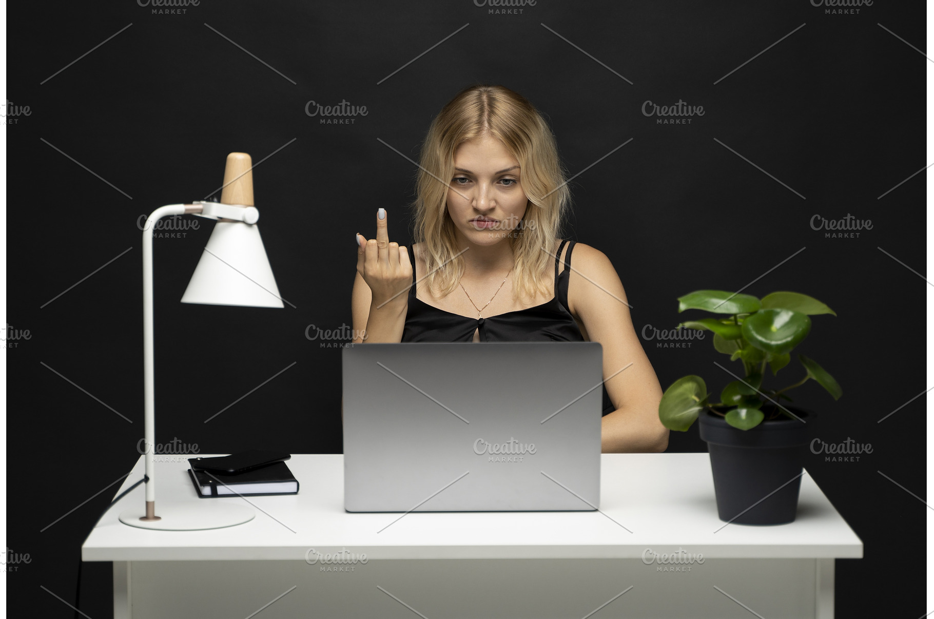 Angry young woman at desk showing, a Business Photo by volodymyrshtun13795