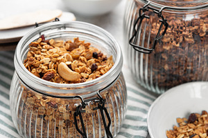 Granola with nuts and dried fruits in glass jars, a Food & Drink Photo by Olena Rudo