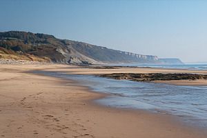 Jurassic Coast beach landscape with sandy shore, cliffs, stream,, a Photo by Studio ANNA