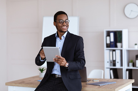 Joyful african american young businessman using digital tablet in office, a Photo by Prostock-Studio