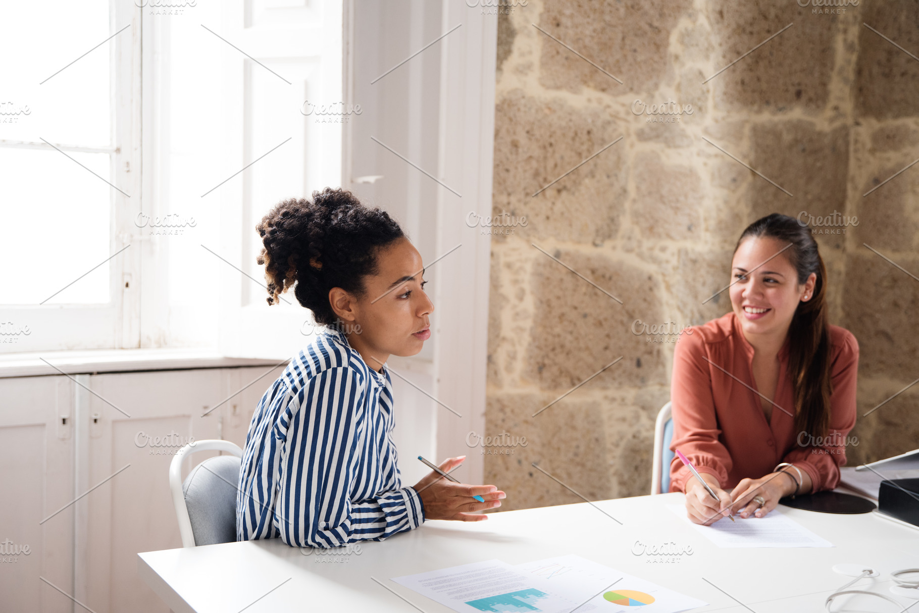 Two women sitting at a table talking, a Person Photo by Coco Images