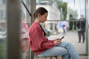 Young girl sitting at bus stop, a Person Photo by HalfPoint