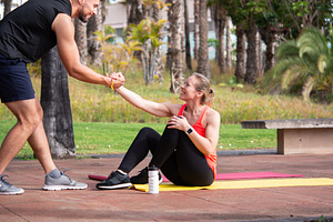 Personal trainer helping mature woman during outdoor fitness workout in park, a Person Photo by etorres69