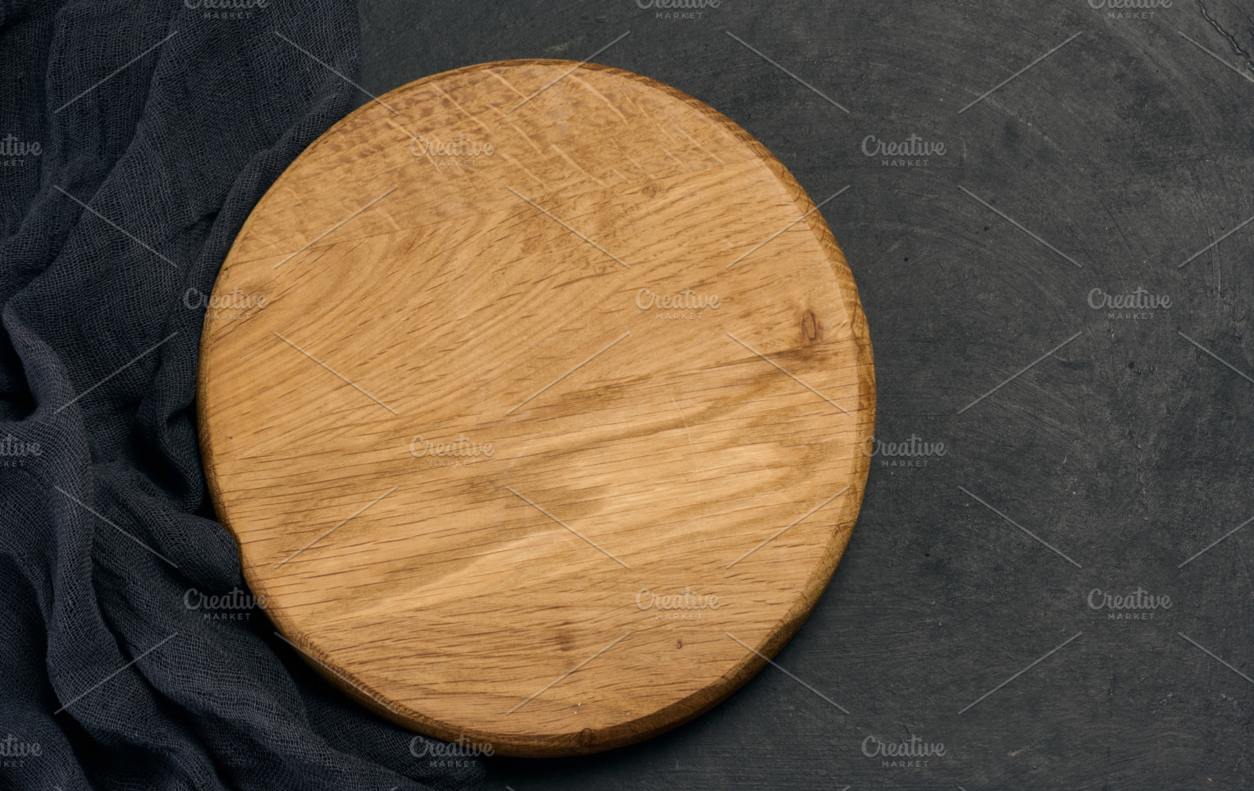 Empty round brown wooden cutting board on a black background, a Food & Drink Photo by ndanko