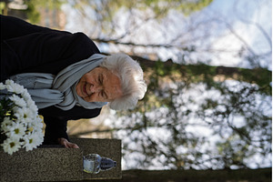 Elderly woman visiting a grave on, a Holiday Photo by HalfPoint