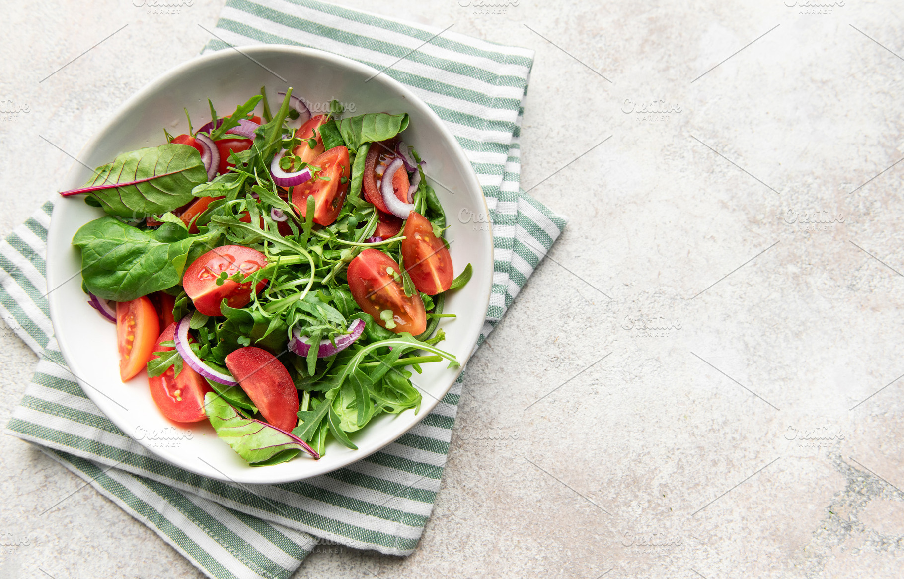 Bowl holding healthy green salad on striped napkin, a Food & Drink Photo by Olena Rudo