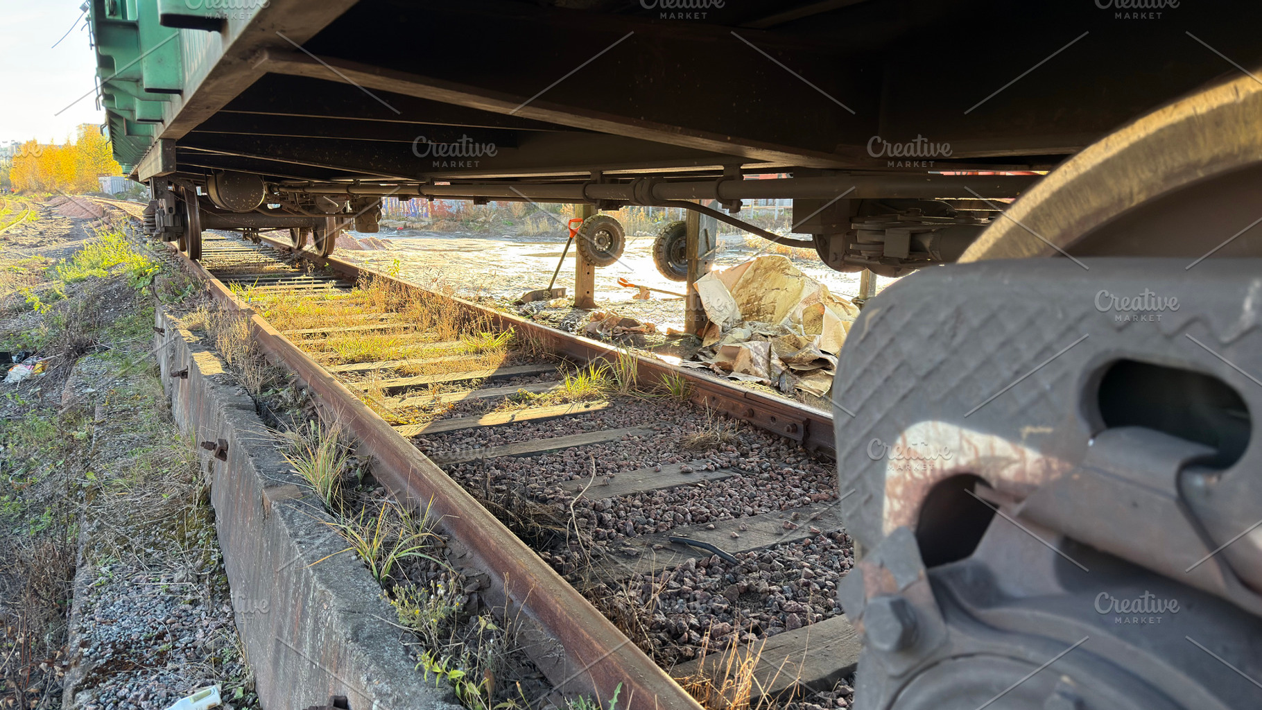 An abandoned railway track with overgrown grass and weeds, showing the undercar, an Industrial Photo by Textures & Backgrounds