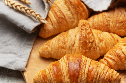 Freshly baked croissants resting on wooden cutting board with wh