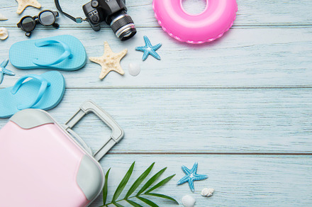 Pink suitcase, blue flip flops, pink lifebuoy and camera resting