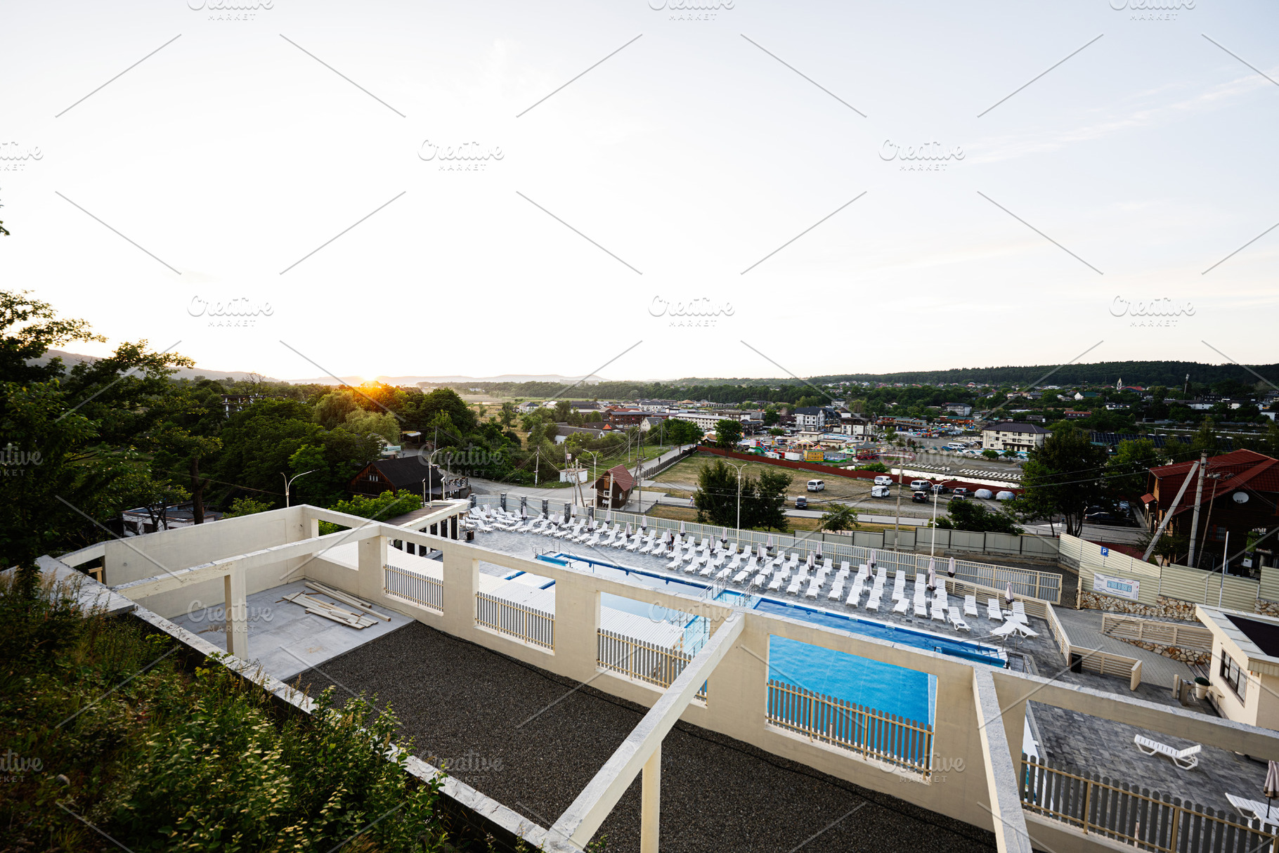 Spacious outdoor pool area overlooking a scenic village at sunset, a Photo by AS photostudio