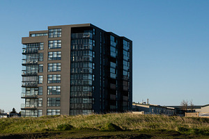 Modern multistory apartment building in Akranes, Iceland during a sunny day, a Photo by AS photostudio
