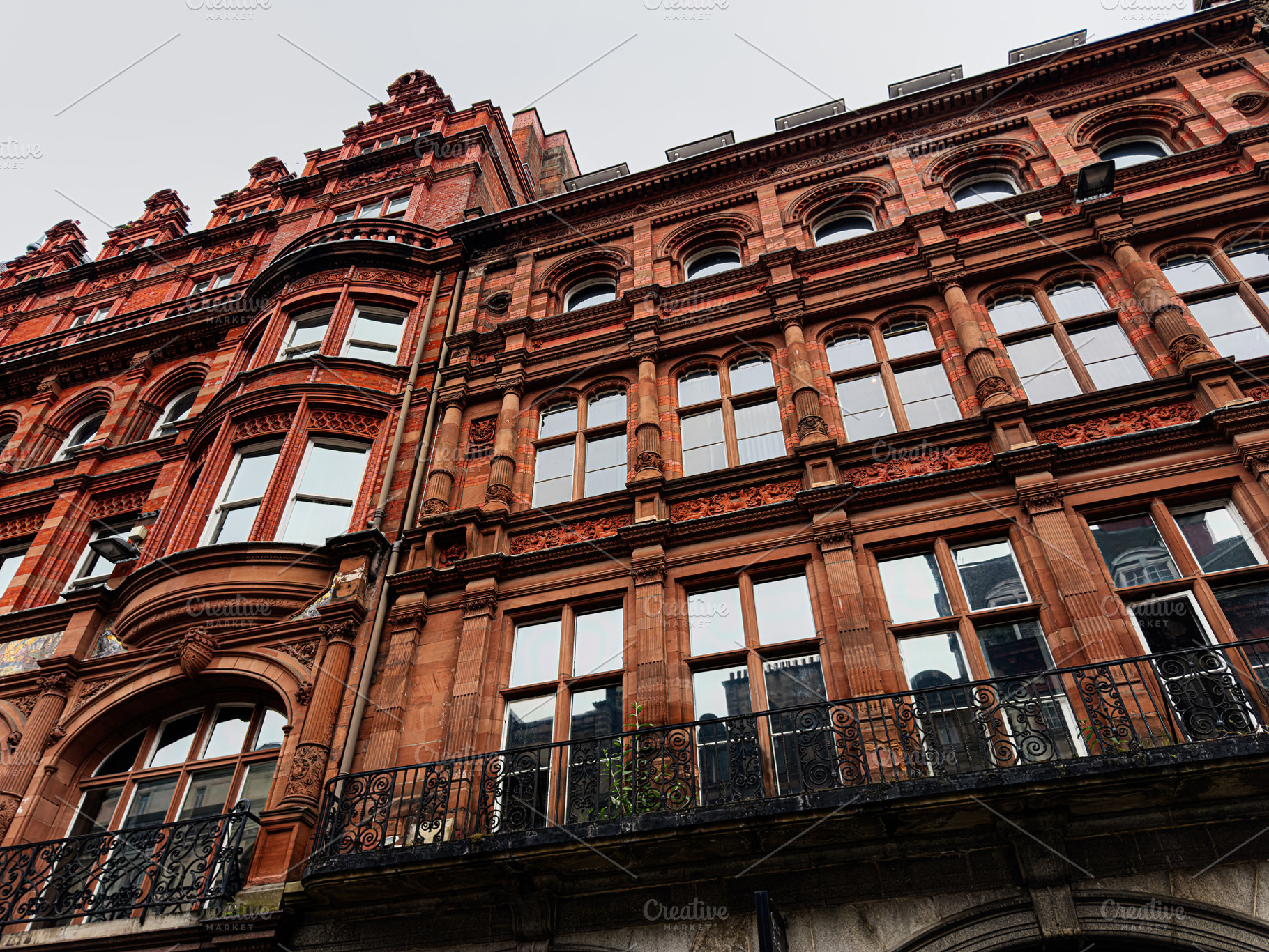Victorian red brick building facade with ornate windows and iron balcony in Liv, a Photo by AS photostudio